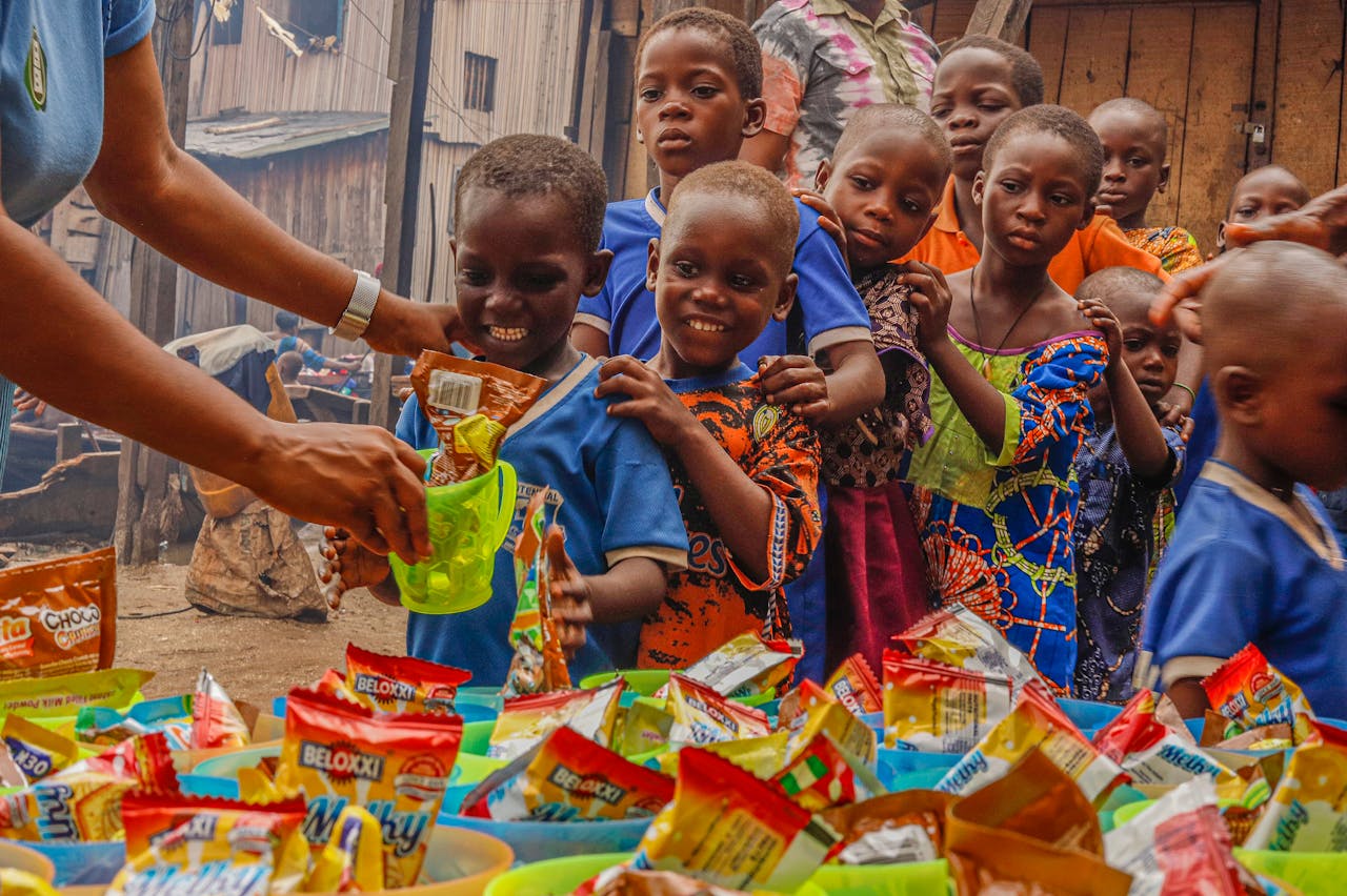 services-02 Joyful children receiving food supplies from a volunteer in an outdoor setting.